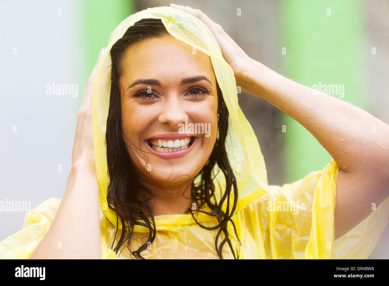 glückliche junge Frau im Regenmantel im freien Stockfoto