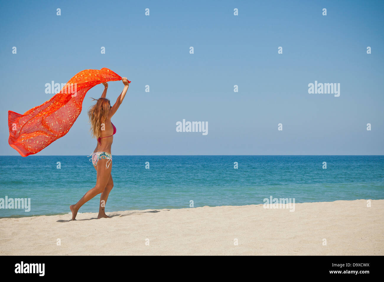 Frau am Strand mit Sarong läuft Stockfoto