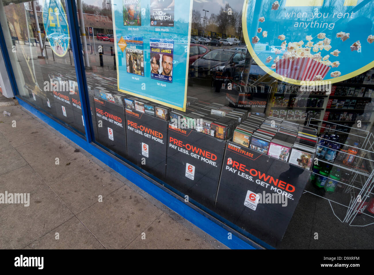 Plakate im Blockbuster Schaufenster Werbung ihre gebrauchte Lager mit der Beschriftung "Lohn weniger, mehr" Stockfoto