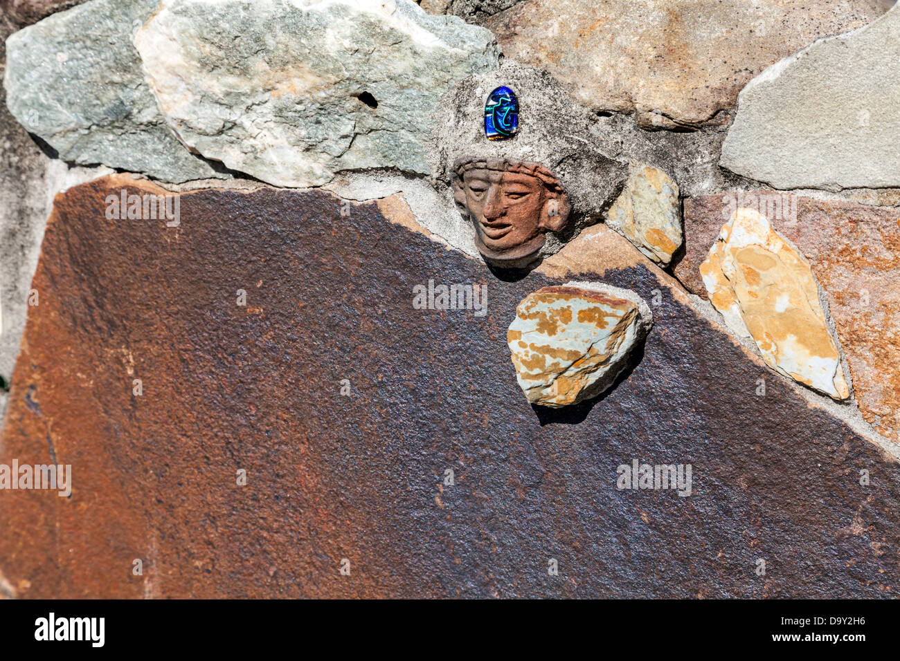 Kleine geschnitzte indische Kopf mit blauen Stein in einer Steinmauer, die die Kinder Garten in Kanapaha Gärten eingebettet. Stockfoto