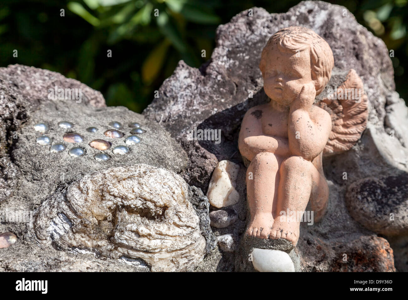 Ein geflügelter Putto und poliertem Glas Kiesel auf eine niedrige Stein Gartenmauer in Kanapaha Gärten in der Nähe von Gainesville, Florida. Stockfoto