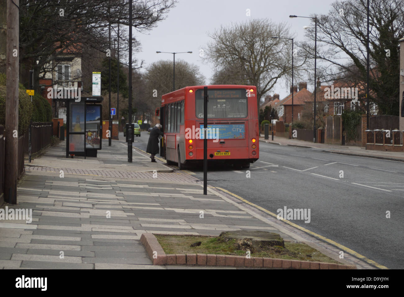 Alte Frau einsteigen in einen roten Bus an einer Bushaltestelle. Stockfoto