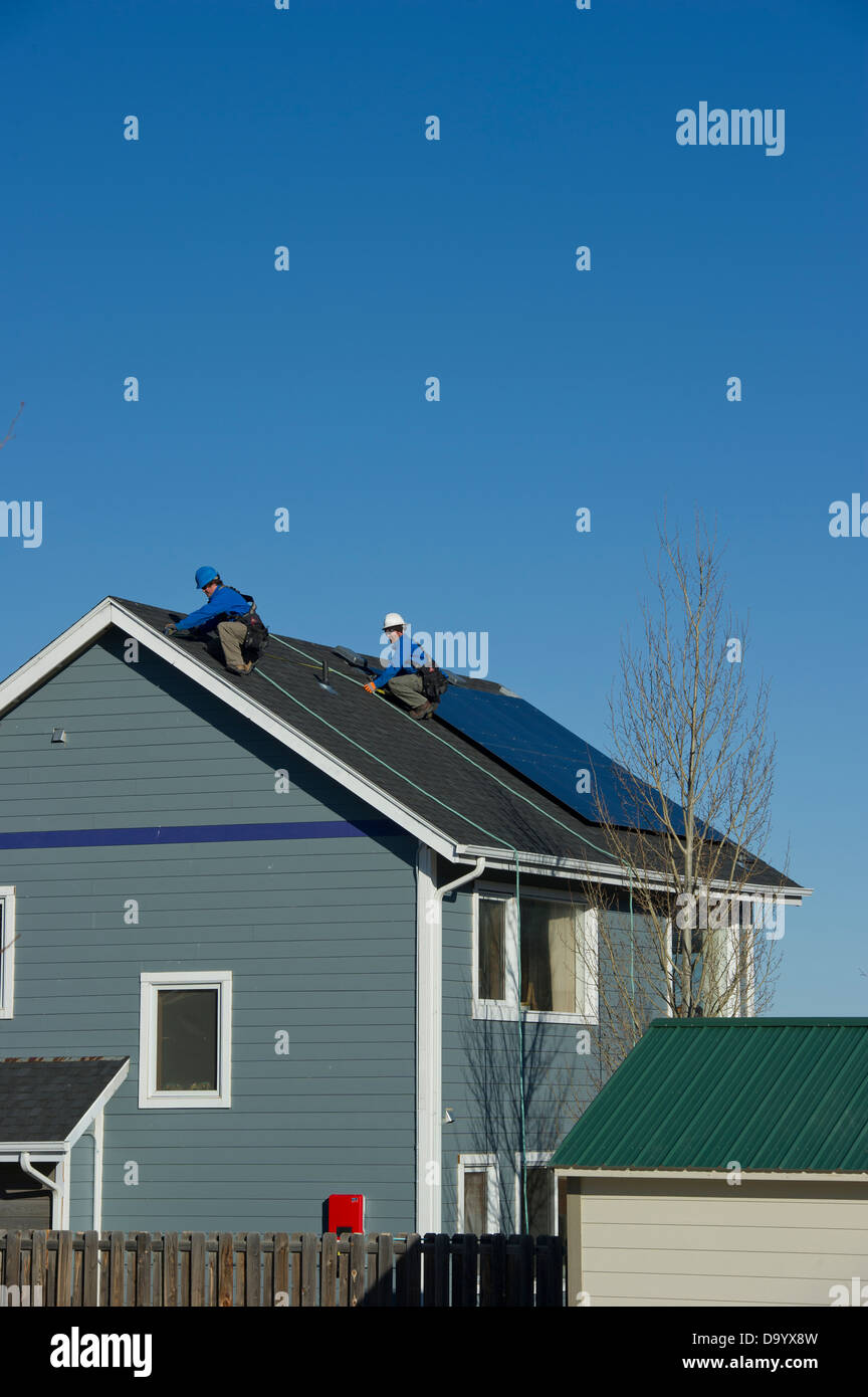 Solar-Installateure arbeiten um eine Solaranlage auf einem Haus zu erweitern. Stockfoto