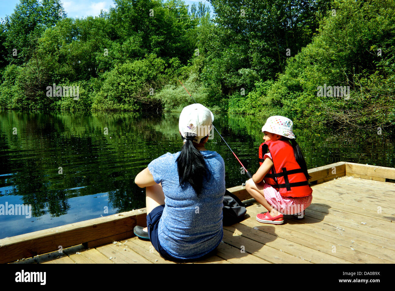 Asiatische Mädchen Mutter BC Fischerei Gesellschaft Binnenfischerei in Stadt Dock Learn Fisch Programm Heiligtum Teich Vancouver Stockfoto