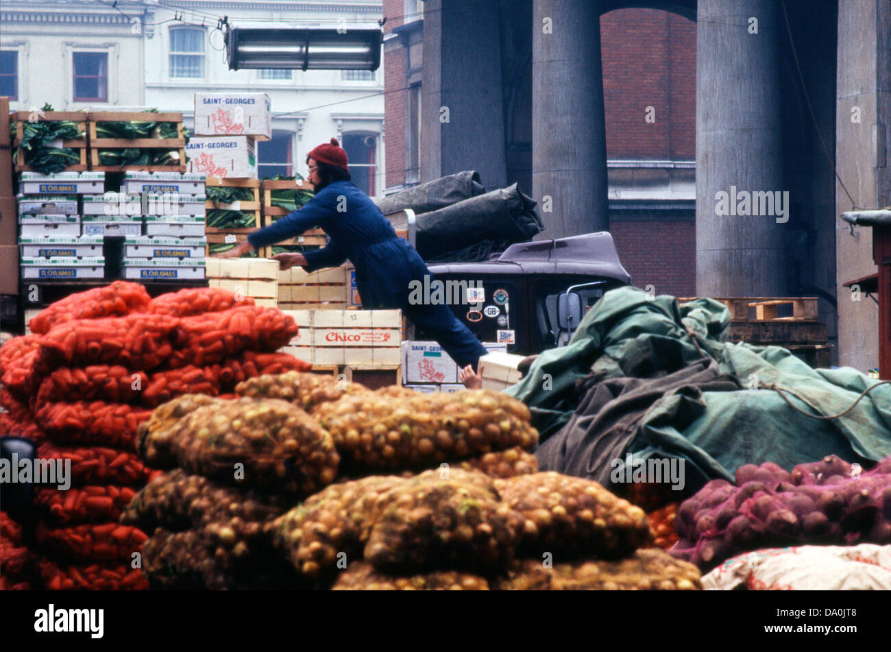 Ein Vintage-Foto eines LKW-Fahrers oder Marktarbeiters beim Entladen von Lebensmittelkisten und Gemüsesäcken Zwiebeln Karotten vor der St. Paul's Kirche auf dem alten Covent Garden Market Gemüsemarkt in London England 1970s 1972 KATHY DEWITT Stockfoto