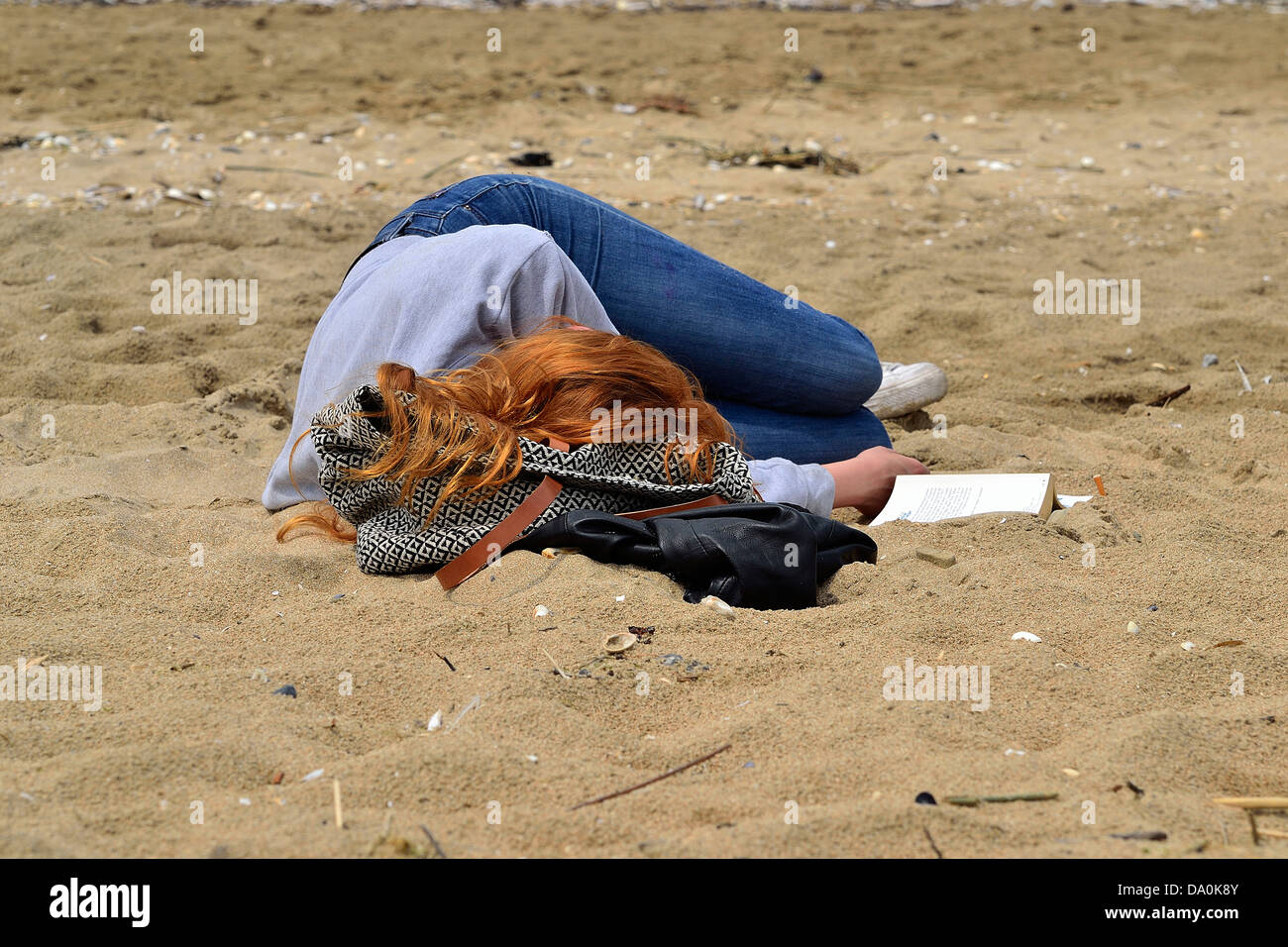 Eine Frau nimmt ein Nickerchen am Strand (Trouville-Sur-Mer, Calvados, Normandie, Frankreich). Stockfoto