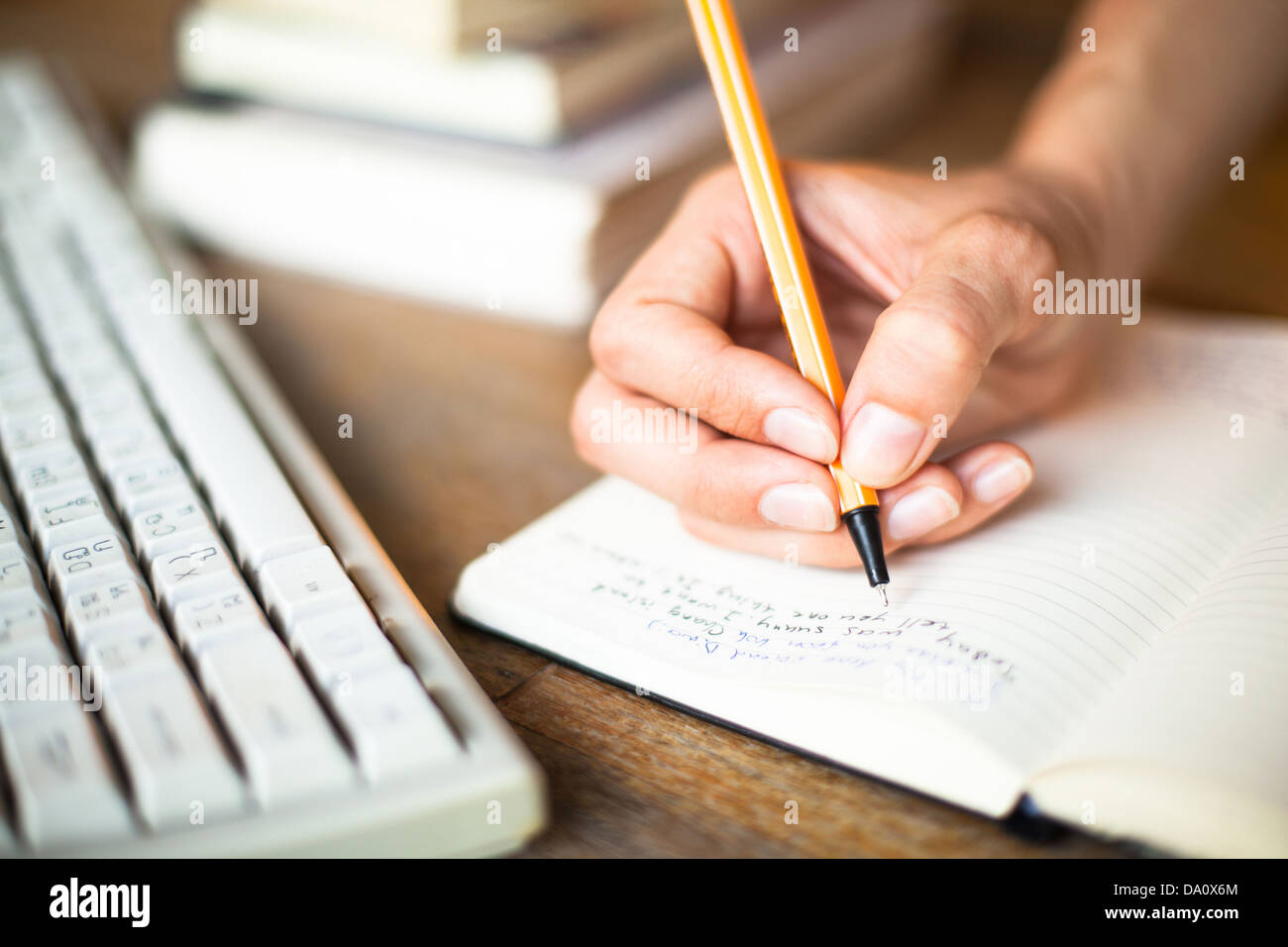 Frau Hände schreibt einen Stift in einem Notebook, Computer-Tastatur im Hintergrund. Stockfoto