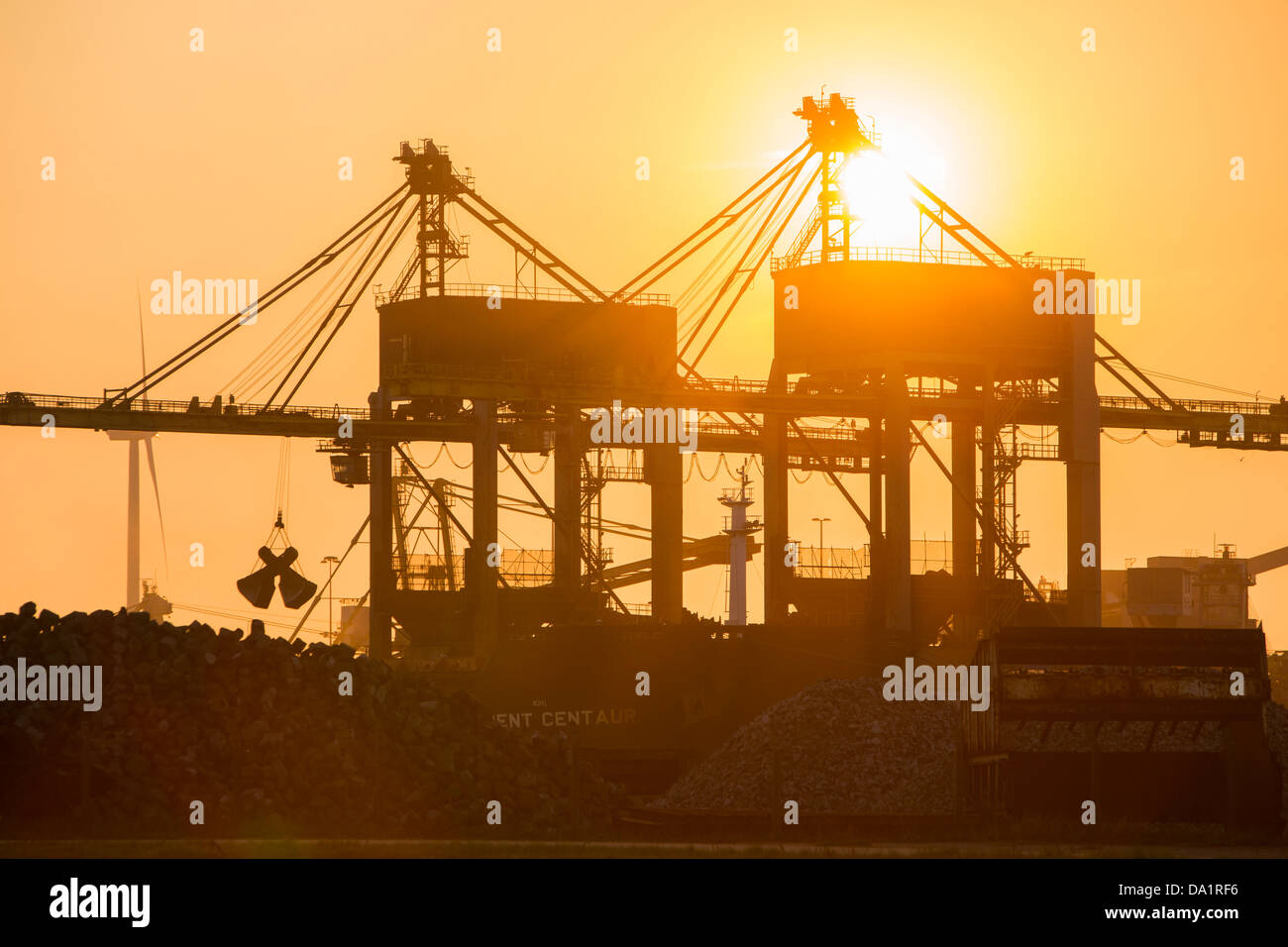 Krane arbeitet entladen Kohle von Tata Steel in Ijmuiden, Niederlande, bei Sonnenuntergang. Stockfoto