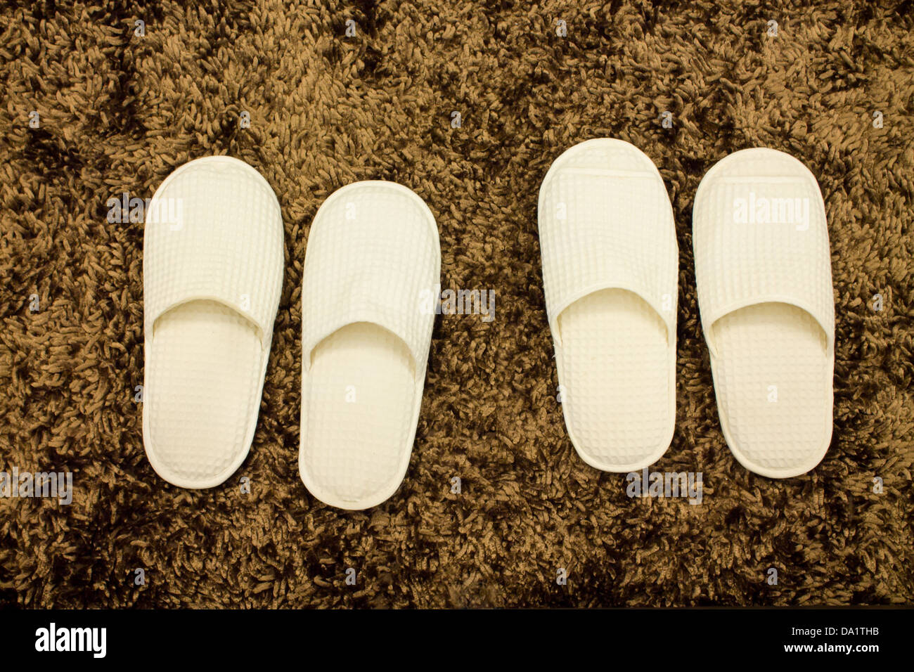 Weiße Slipper auf braune Matte Stockfoto