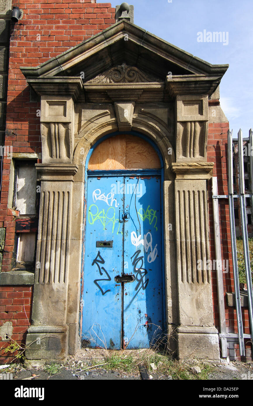 Eine blaue Tür auf einer verlassenen Gebäude mit Graffiti und Sicherheitszaun. Eindeutig nichts dahinter. Stockfoto