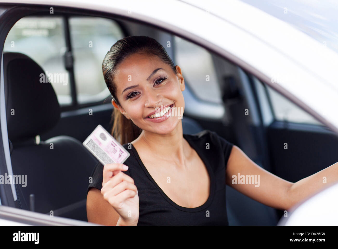 fröhliche junge Frau zeigt einen Führerschein habe sie gerade Stockfoto