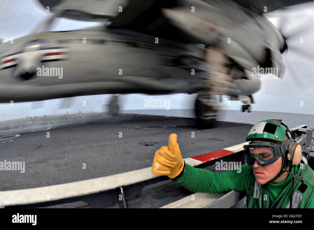 US Marine Aviation Boatswain Mate 3. Klasse Neil Graupmann gibt eine Entwarnung von der Sicherheitsstellung Bogen, ein E - 2 C Hawkeye frühe Warnung Flugzeug aus dem Flugdeck der USS George Washington im Pazifischen Ozean 30. Juni 2013 starten. Stockfoto