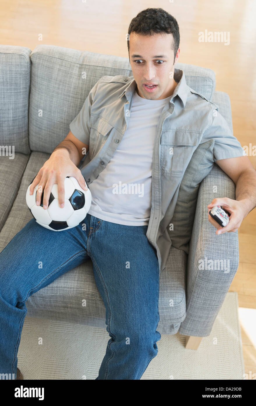 Junger Mann beobachten Fußballspiel im Fernsehen Stockfoto