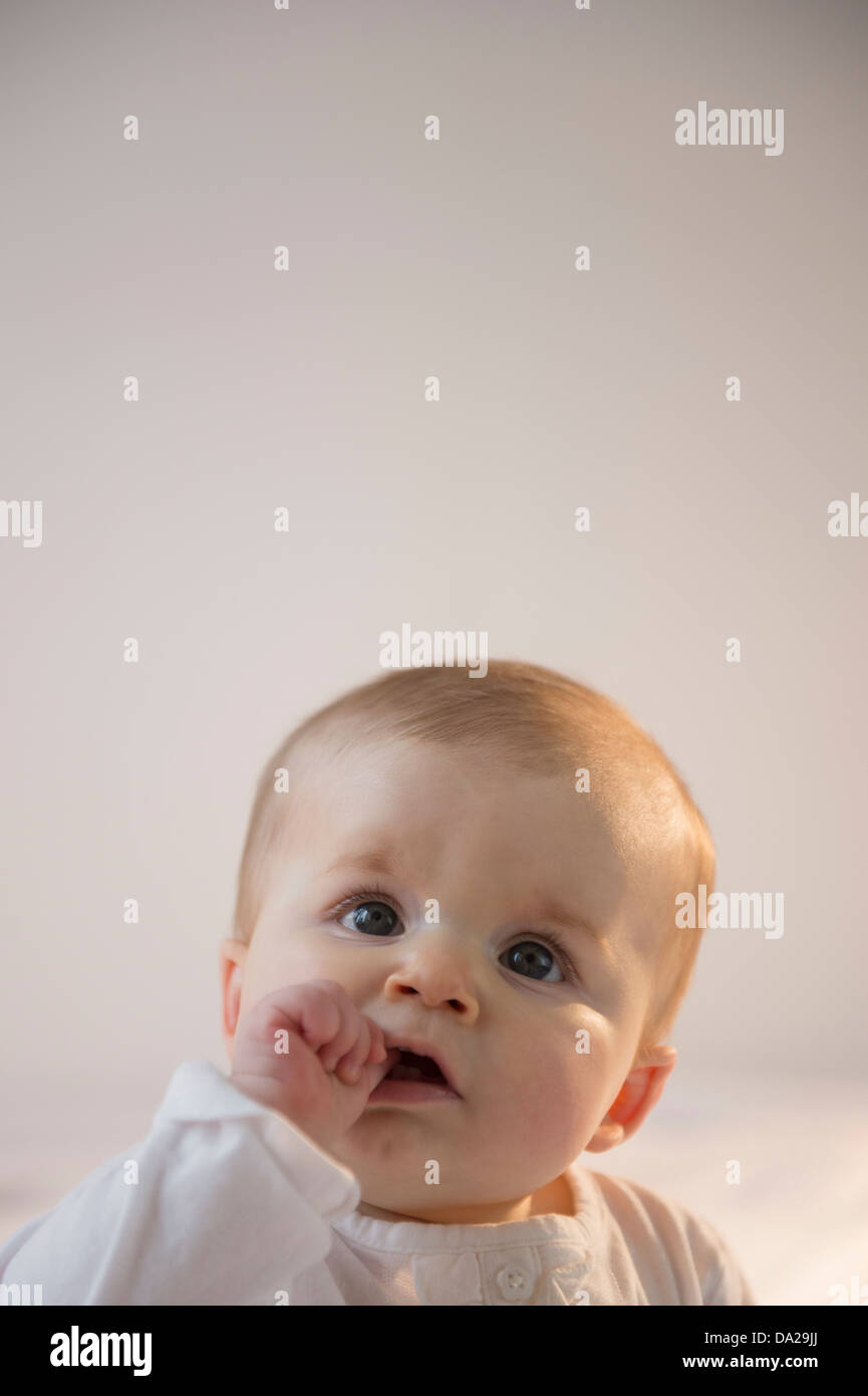 Porträt von Baby Girl (6-11 Monate) sitzen im Bett mit Stapel Bücher Stockfoto