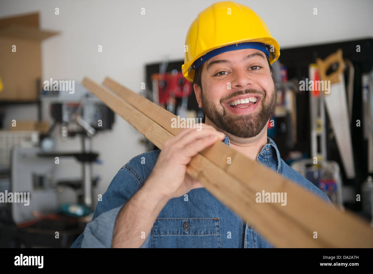 Porträt der lächelnde Arbeiter, hält Bretter auf seiner Schulter Stockfoto