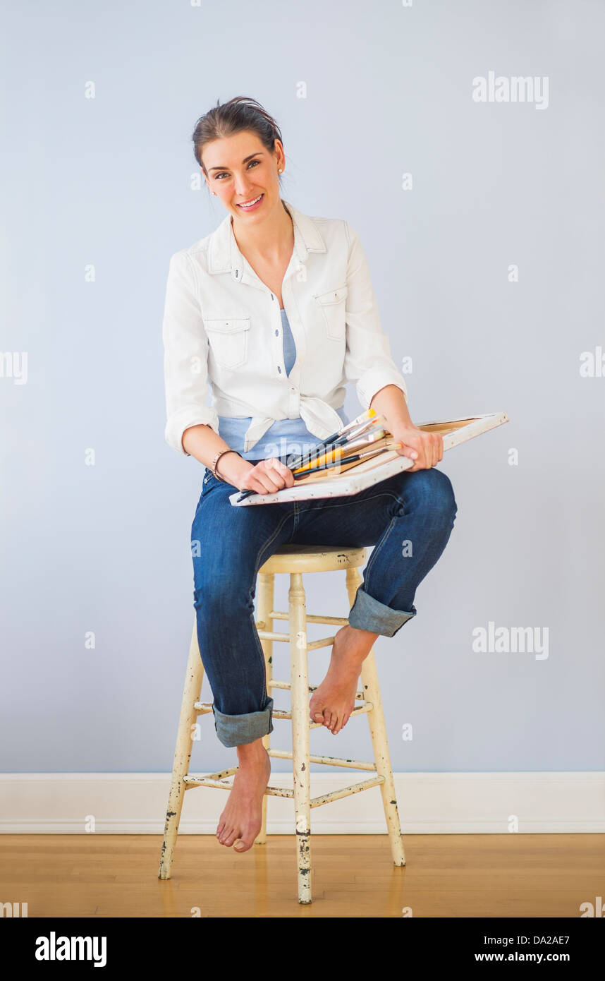 Studioaufnahme Frau sitzen auf Stuhl, mit Pinsel und Leinwand des Künstlers Stockfoto