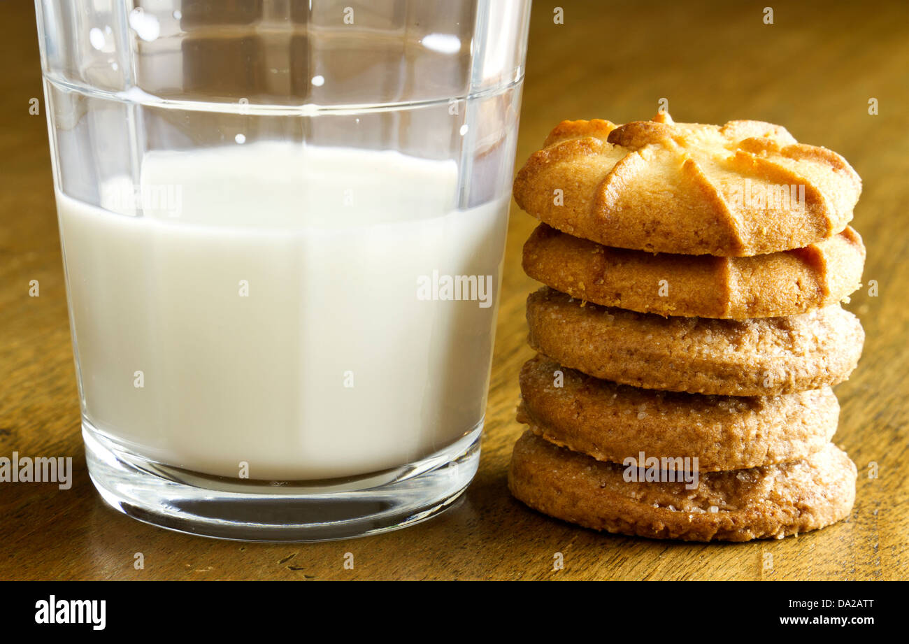 Leckere süße Cookies und Glas kalte Milch auf Holz Tisch gestapelt. Stockfoto