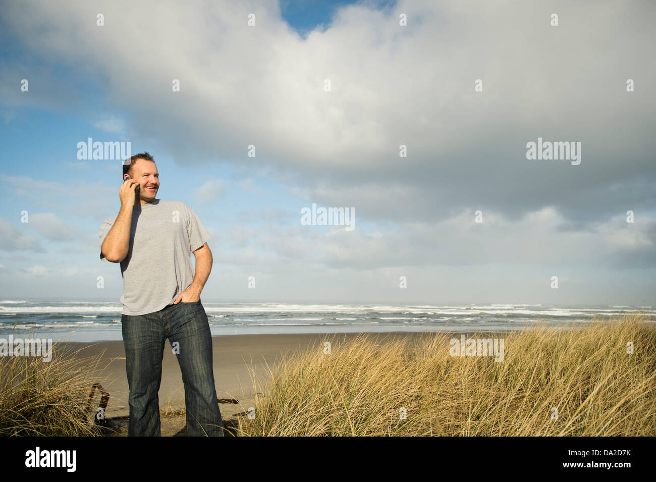 USA, Oregon, Rockaway Beach, Mann am Telefon stehen am Strand Stockfoto