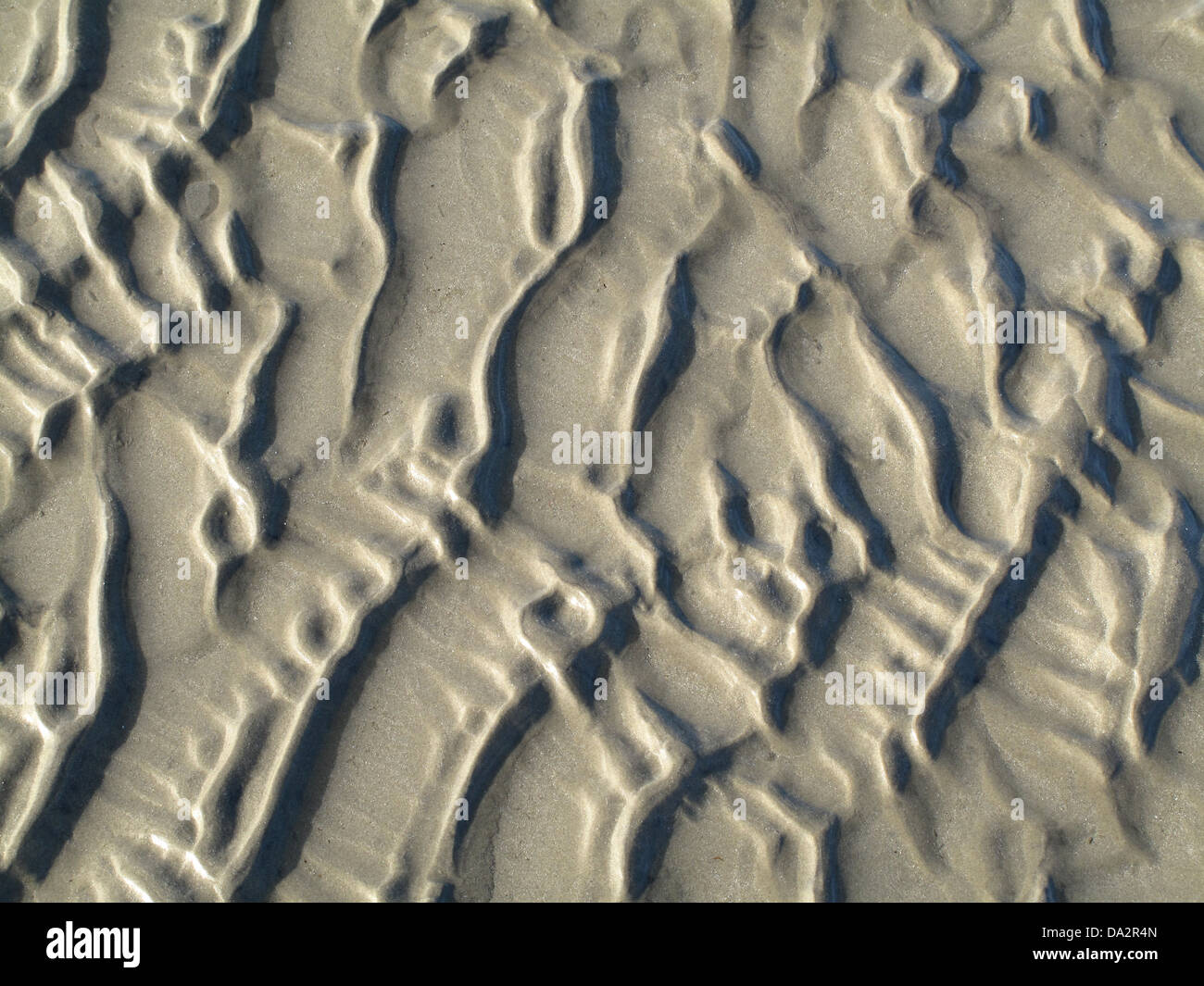 Zufällige, abstrakte Muster, die von der Flut am Sandstrand von Worthing Beach, West Sussex, UK Stockfoto