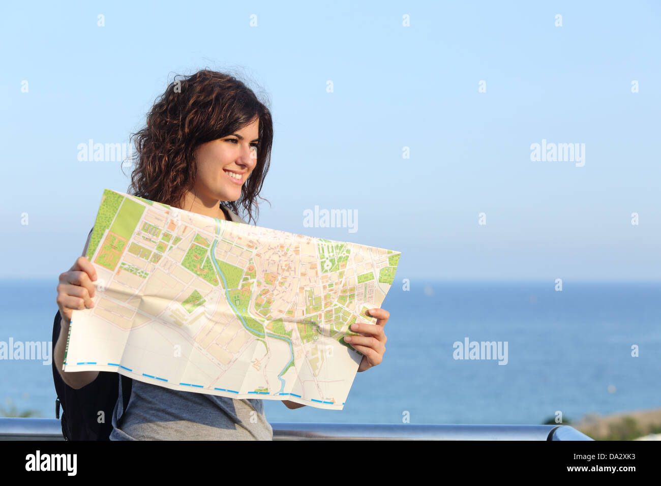 Schönen touristischen Frau im Urlaub mit einem Stadtplan mit dem Meer und Himmel im Hintergrund Stockfoto