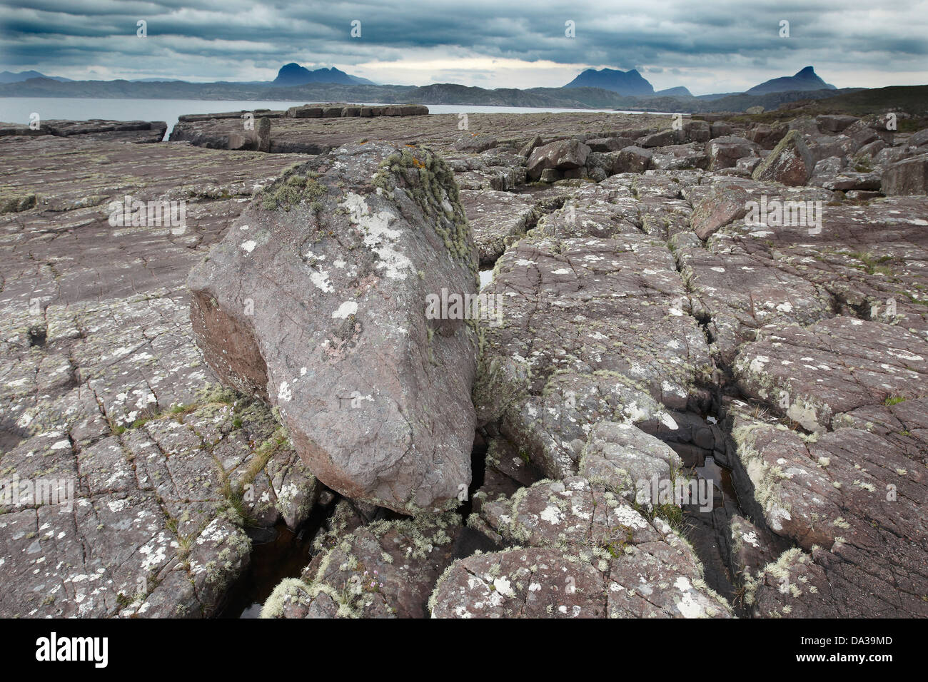 Felsen bedeckt in Flechten unter einem dramatischen Himmel am Ufer des Enard Bay, Sutherland, Nord-West-Schottland Stockfoto