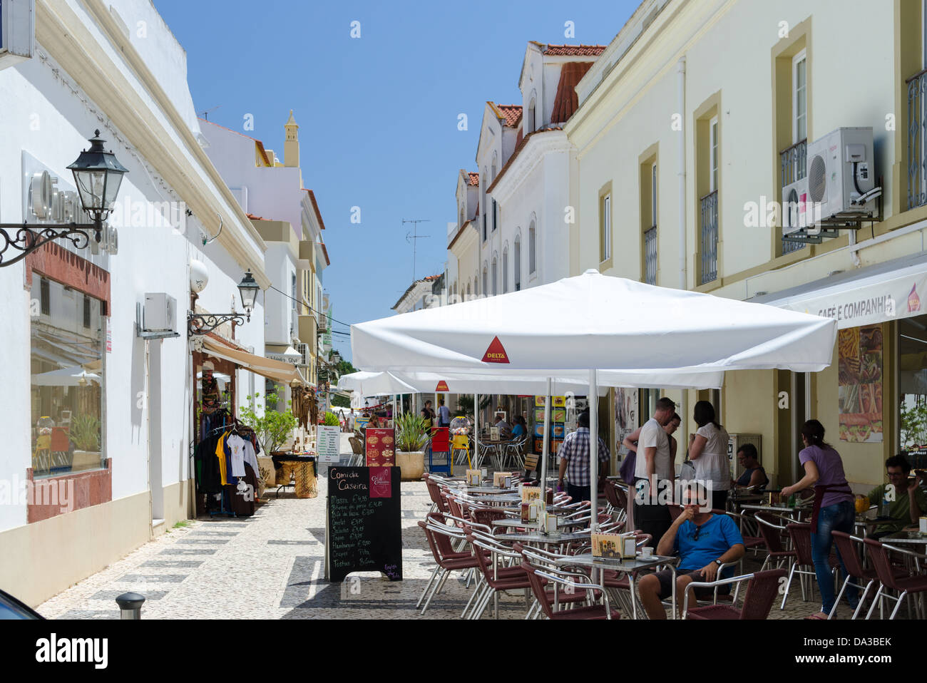 Tische und Stühle vor einem Café auf gepflasterten Fußgängerzone in der alten portugiesischen Stadt Silves Stockfoto