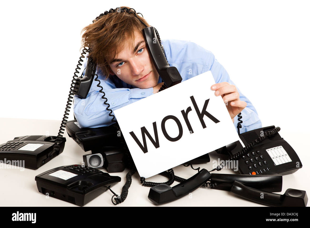 Erschöpften Mann voller Arbeit, sitzen mit einem Bündel von Handys über ihm und hielt einen Karton mit dem Wort Arbeit. Stockfoto