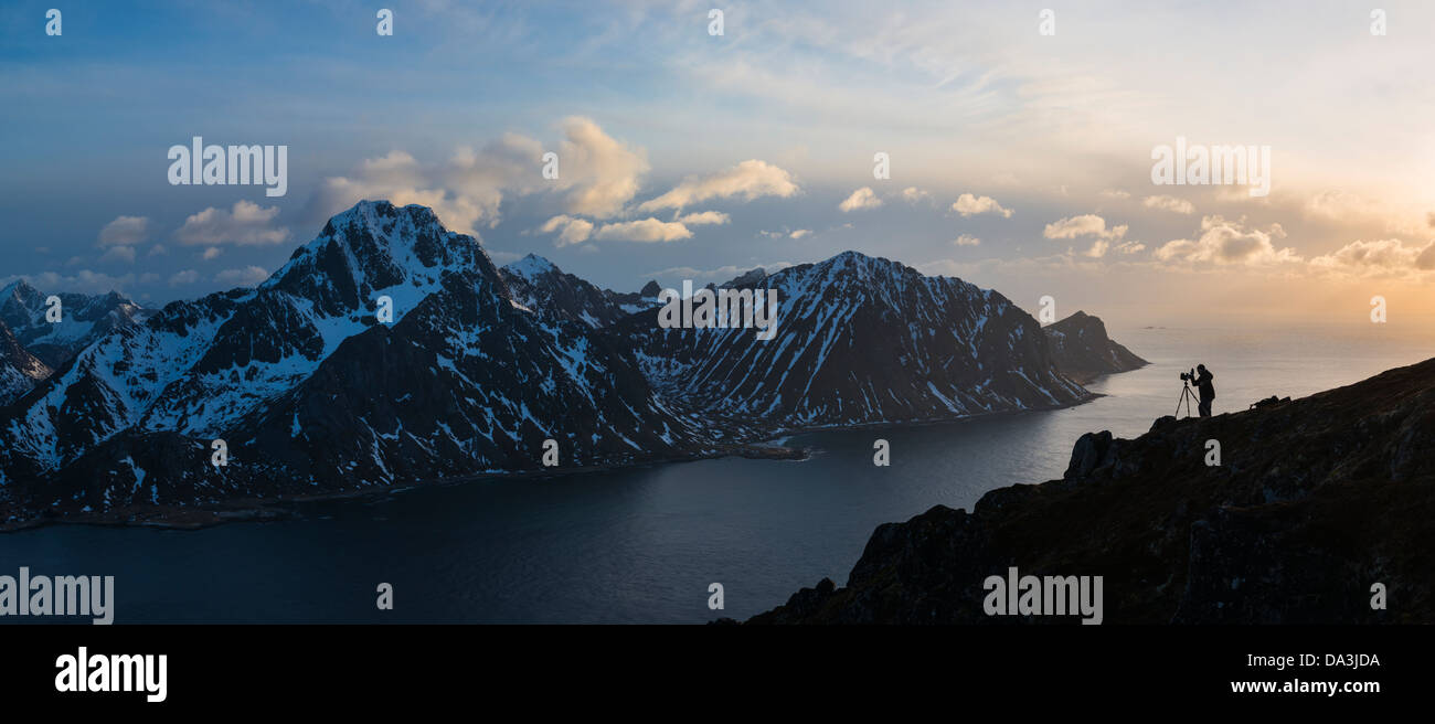 Silhouette der Landschaftsfotograf am Gipfel des Offersoykammen mit Flakstadoy im Hintergrund, Lofoten Inseln, Norwegen Stockfoto