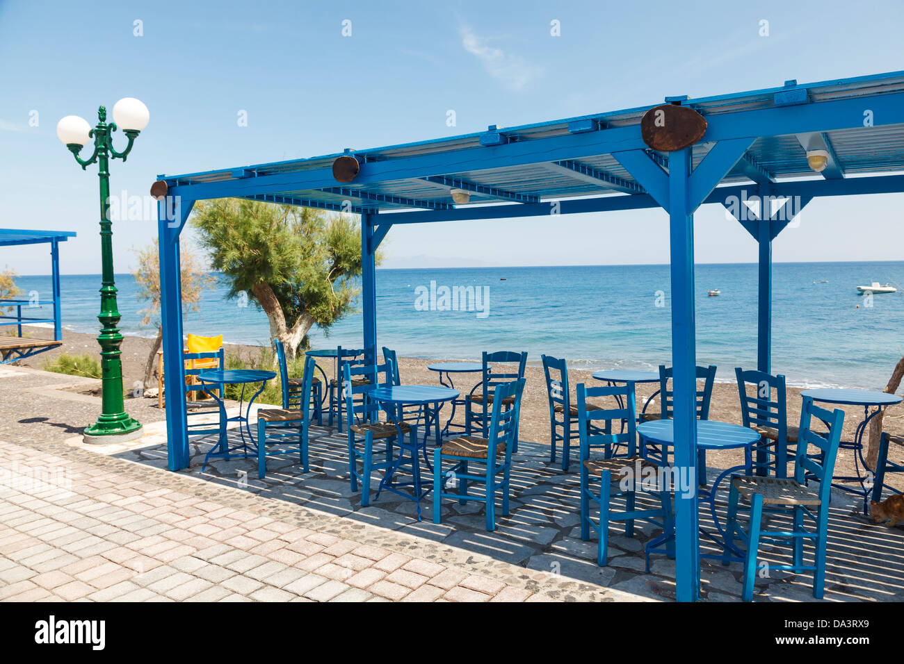 Tischen und Stühlen mit Blick auf Santorini Kamari Beach Griechenland Stockfoto