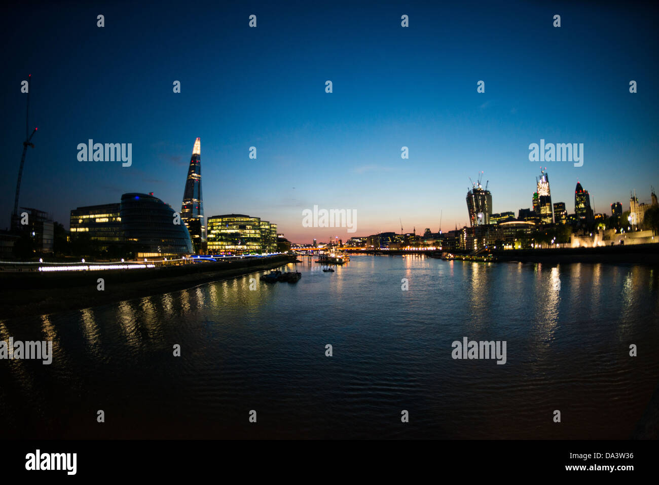 London Skyline in der Abenddämmerung von der Tower Bridge // die Londoner Skyline in der Abenddämmerung, von der Tower Bridge aus gesehen. Queen's Walk befindet sich auf der linken Seite, mit der Halbkuppel des Londoner Rathauses und dem Shard-Standfuß dahinter. Stockfoto