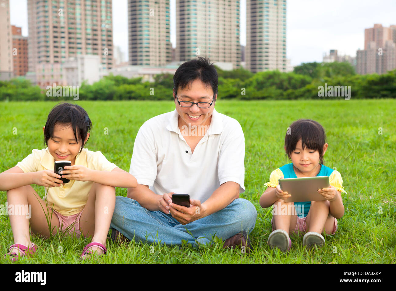 glückliche Familie mit smart Phone und Tablet-pc im freien Stockfoto