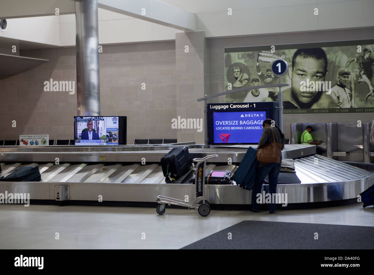 Ein Frau Pick up ihr Gepäck am Gepäckband des Detroit Metropolitan Wayne County Airport "McNamara Terminal Stockfoto