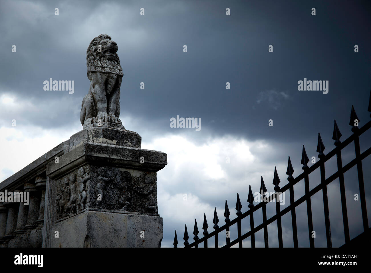Löwenstatue mit Eisenzaun und regnerischen Himmel. Stockfoto