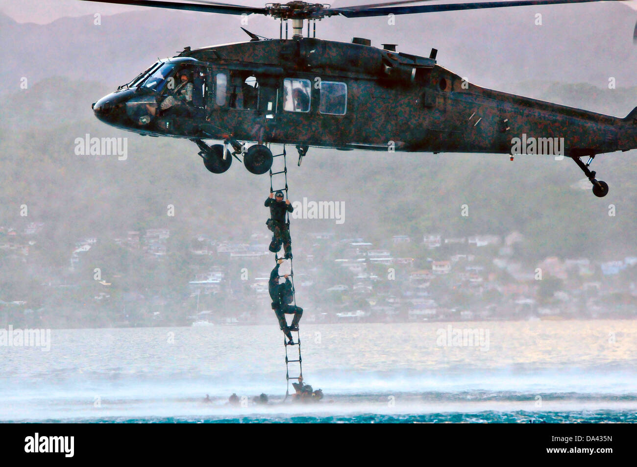 US Navy SEAL Teammitglieder steigen eine Höhlenforschung Leiter zu einem UH-60 Black Hawk Hubschrauber während der HELOCAST Ausbildung im Marine Corps Air Station Kaneohe Bay 19. Juni 2013 in Hawaii. Stockfoto