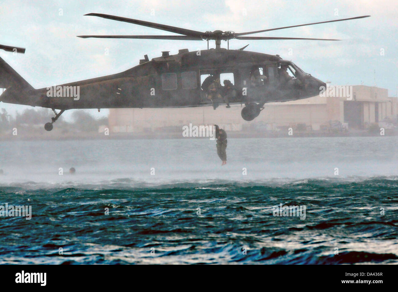 Ein uns Armee UH-60 Black Hawk-Hubschrauber mit dem 25. Combat Aviation Brigade Tropfen Navy SEAL Special Warfare Group 3 Mitglieder ins Wasser während des Trainings HELOCAST im Marine Corps Air Station Kaneohe Bay 19. Juni 2013 in Hawaii. Stockfoto