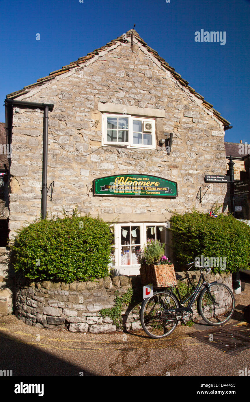 Eine altmodische Fahrrad lehnt sich an die Wand des Bloomers Bakewell Pudding Shop in Bakewell, Derbyshire, England, UK Stockfoto