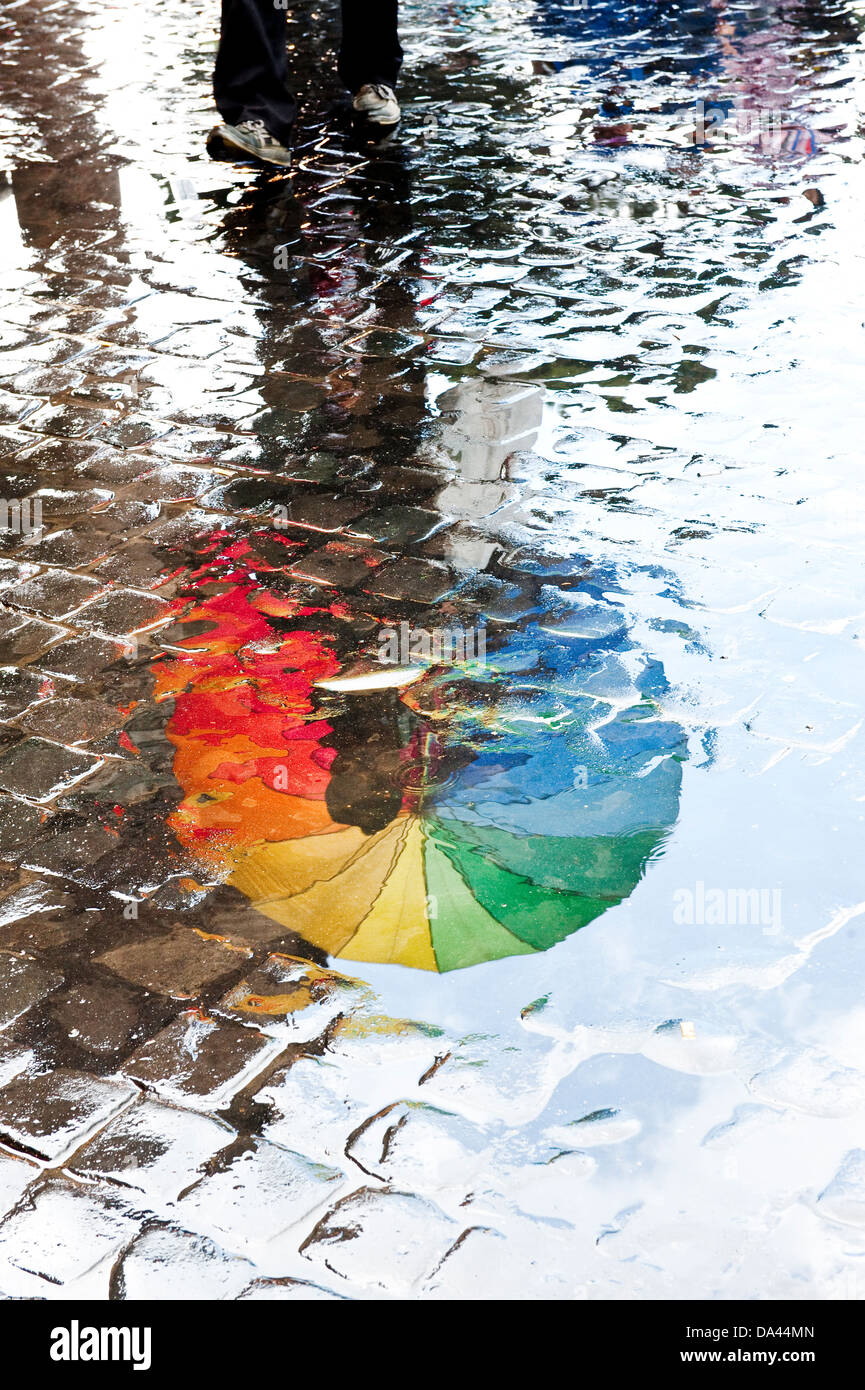Regenbogen Regenschirm Reflexionen in Pfützen Wasser, Rom, Italien Stockfoto