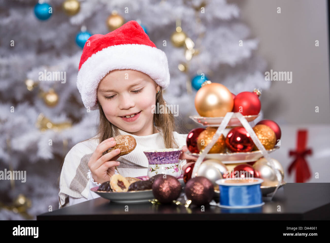 kleines Mädchen mit Santa Cap am Weihnachtsbaum Stockfoto