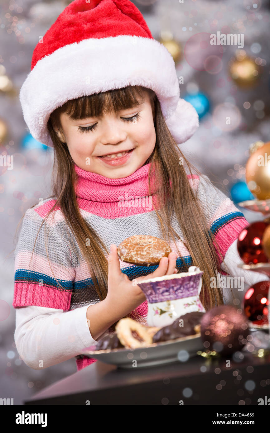 kleines Mädchen mit Santa Cap am Weihnachtsbaum Stockfoto