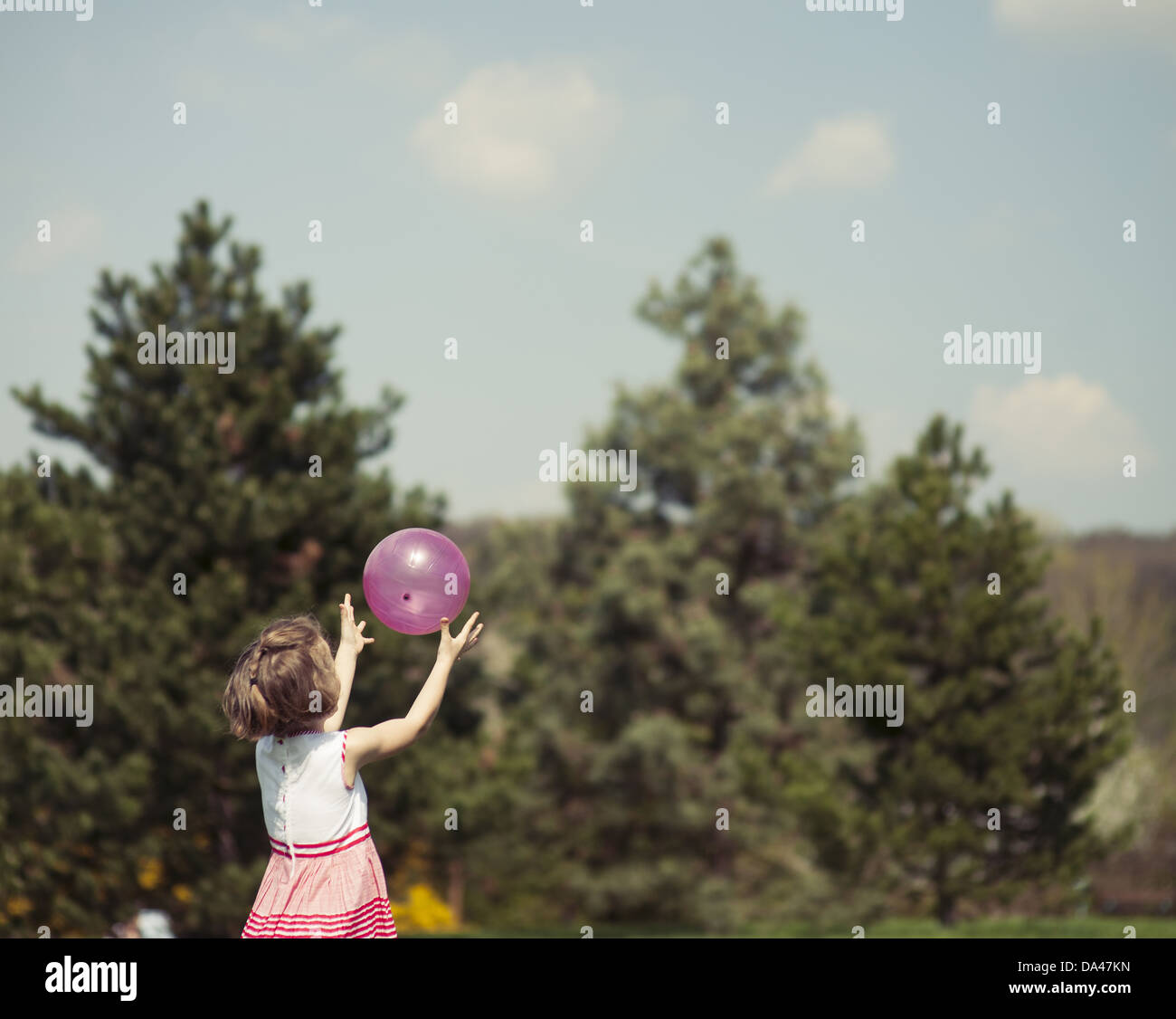 Junges Mädchen fangen lila Ball im park Stockfoto