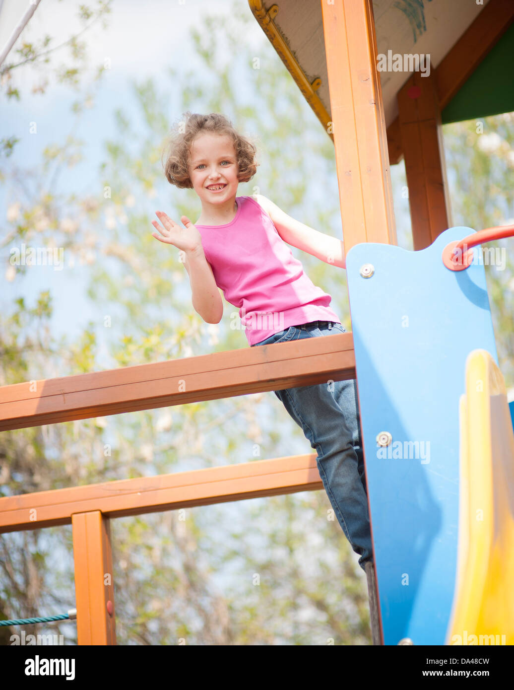 Junges Mädchen Klettern am Kinderspielplatz und winken in die Kamera Stockfoto