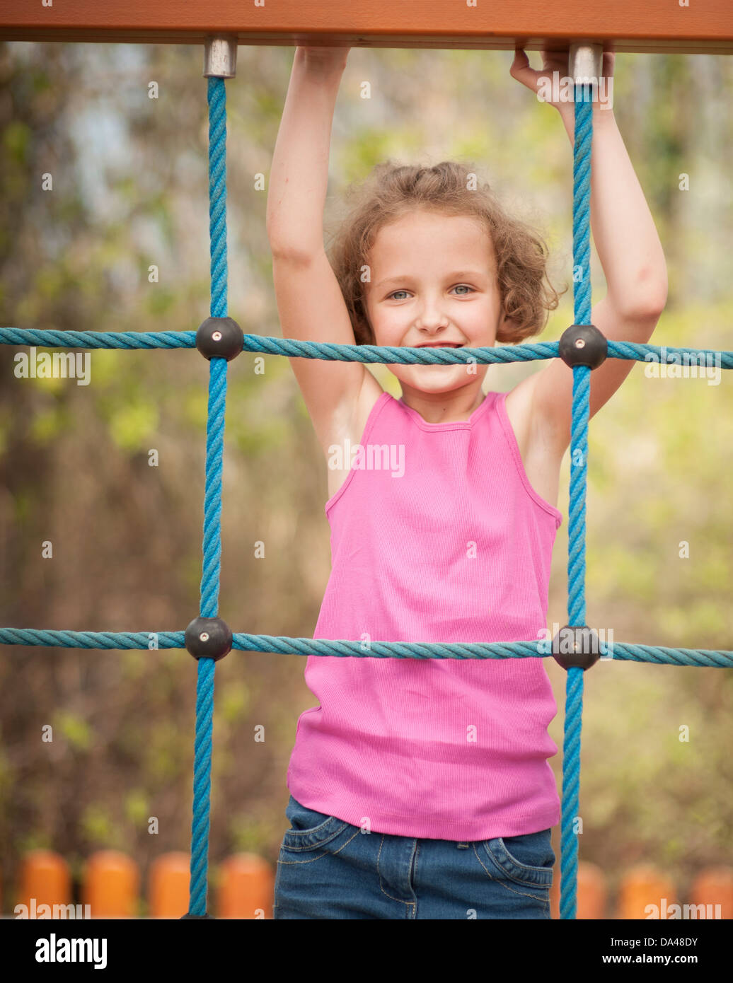 Halblanger Schuss des jungen Mädchens auf Kletternetz Stockfoto