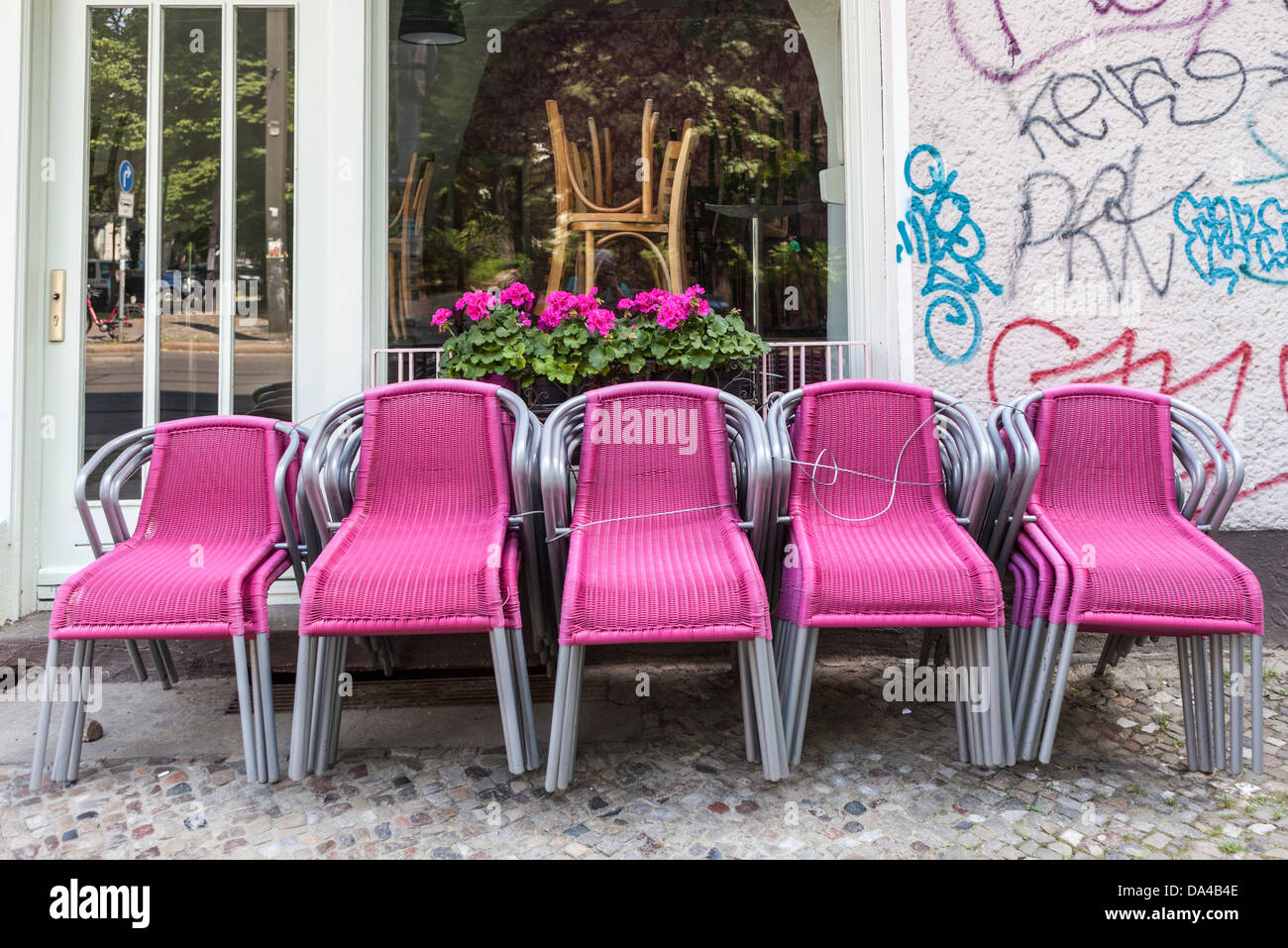 Graffiti, rosa Stühle und rosa Geranien vor einem geschlossenen Restaurant in Berlin-Mitte Stockfoto