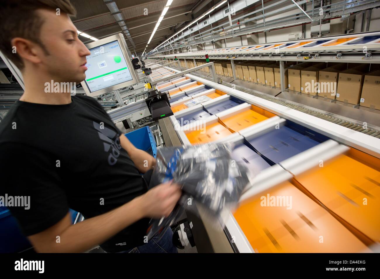 Adidas Mitarbeiter Antonio Lucic setzen Produkte auf ein Förderband in  Rieste, Deutschland, 3. Juli 2013. Mit einem Investitionsvolumen von mehr  als 100 Millionen Euro hat der Welt größte Adidas Group-Logistikzentrum  eröffnet. Foto.