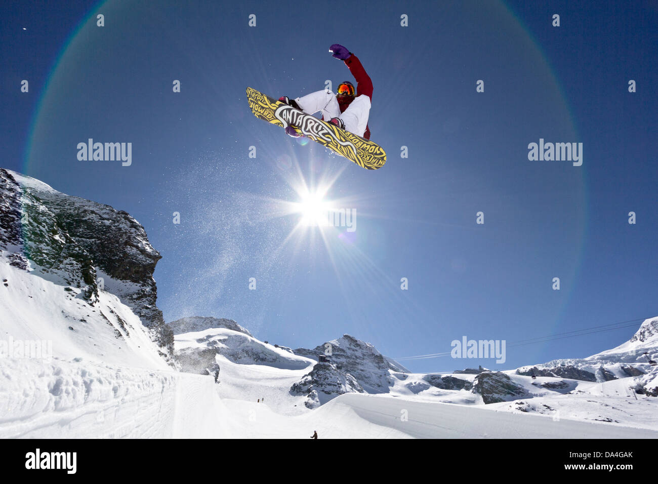 SAAS-FEE, WALLIS, SCHWEIZ. Weiblichen Snowboarder fahren die Halfpipe mit einem Stalefish-Trick. Im Hintergrund die Sonne. Stockfoto