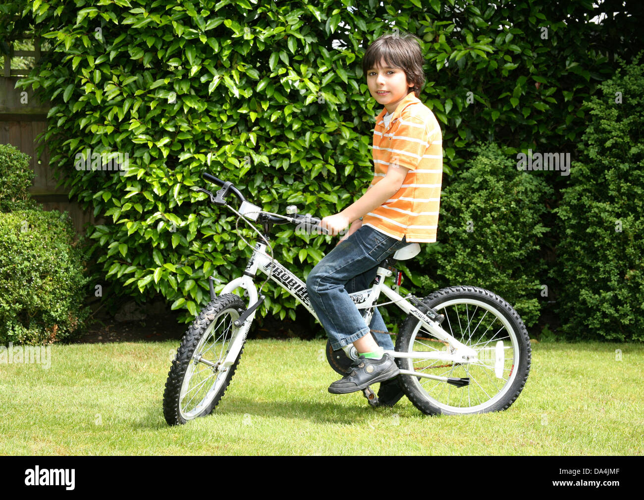 Porträt von Brünette Junge auf Fahrrad in sonnigen Hinterhof Stockfoto