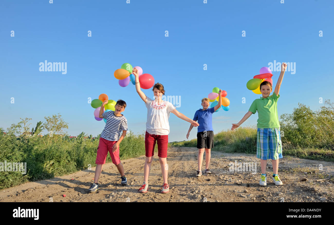glückliche Kinder mit bunten Luftballons in einem Feld Stockfoto