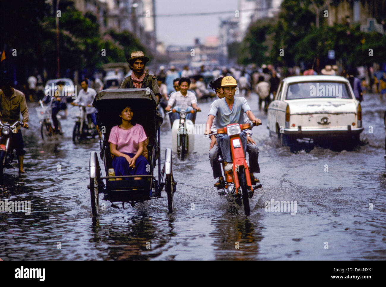 Phnom Penh; Verkehr von Rikschas, Fahrräder und Autos bewegt sich durch überflutete Straßen nach dem Monsunregen. Stockfoto