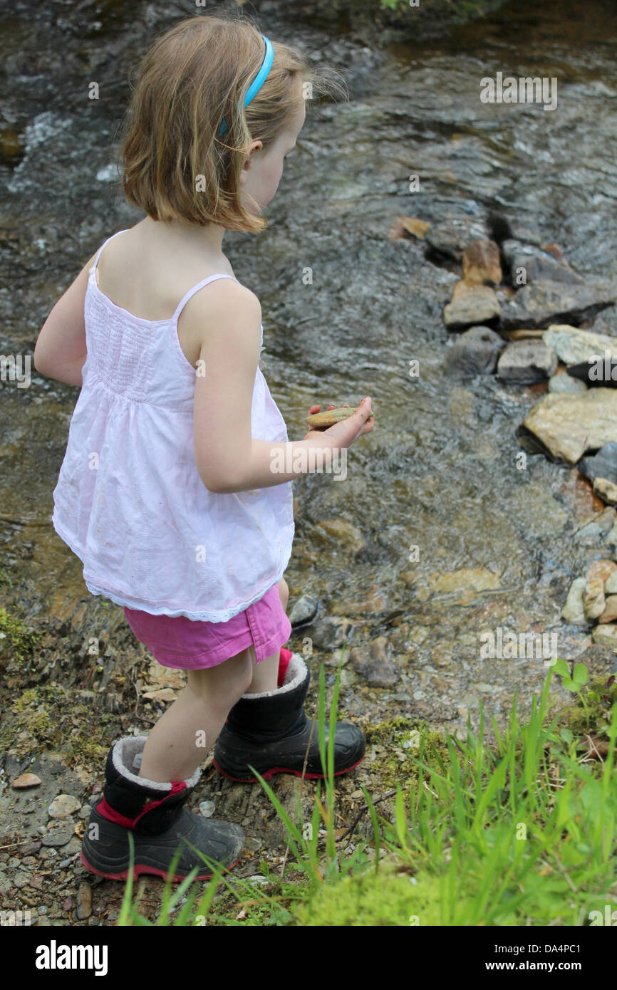 Junge Mädchen tragen Kiesel am Fluss Stockfoto