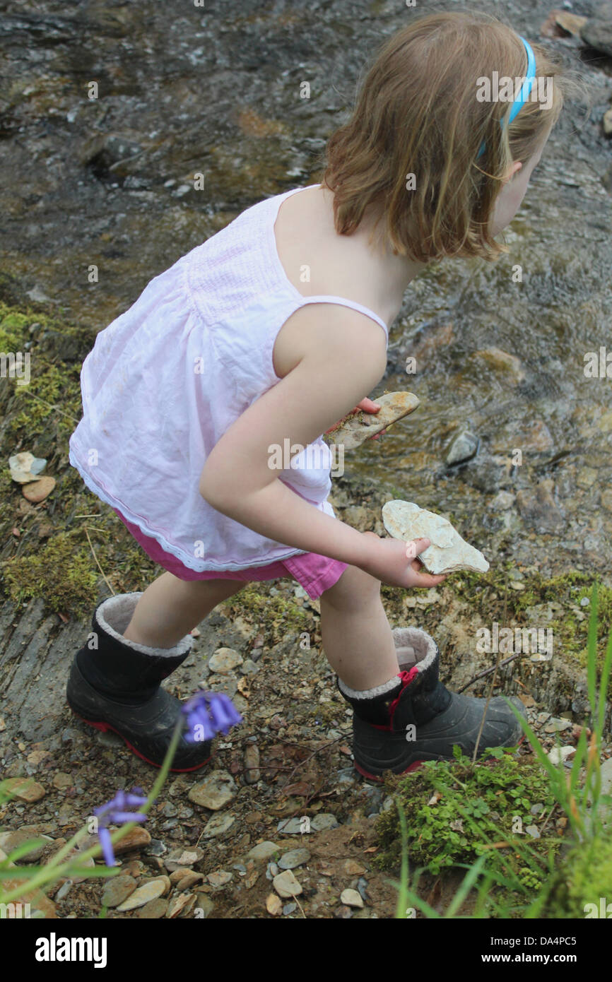 Junges Mädchen mit Steinen an einem Bach Stockfoto